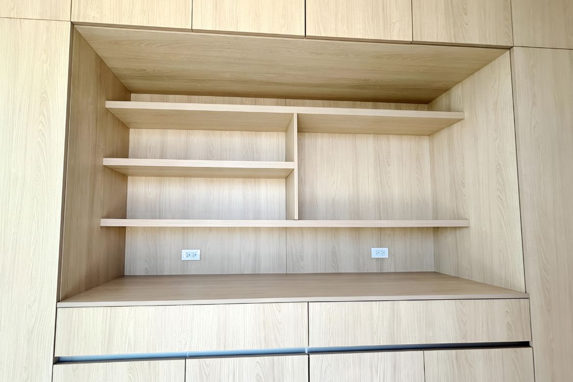 Custom built-in desk and storage cabinetry with open shelving and integrated power outlets