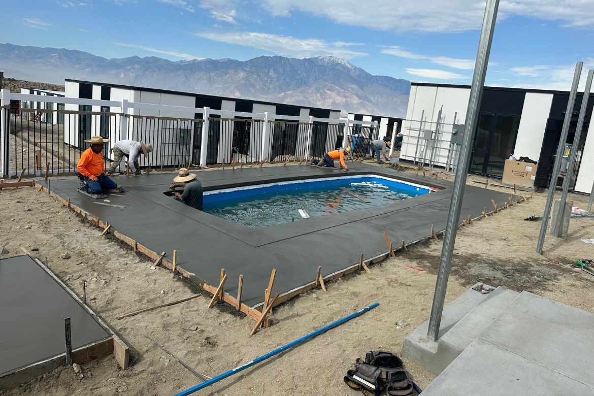 Residential pool construction with concrete deck pour and formwork in progress at modern home site